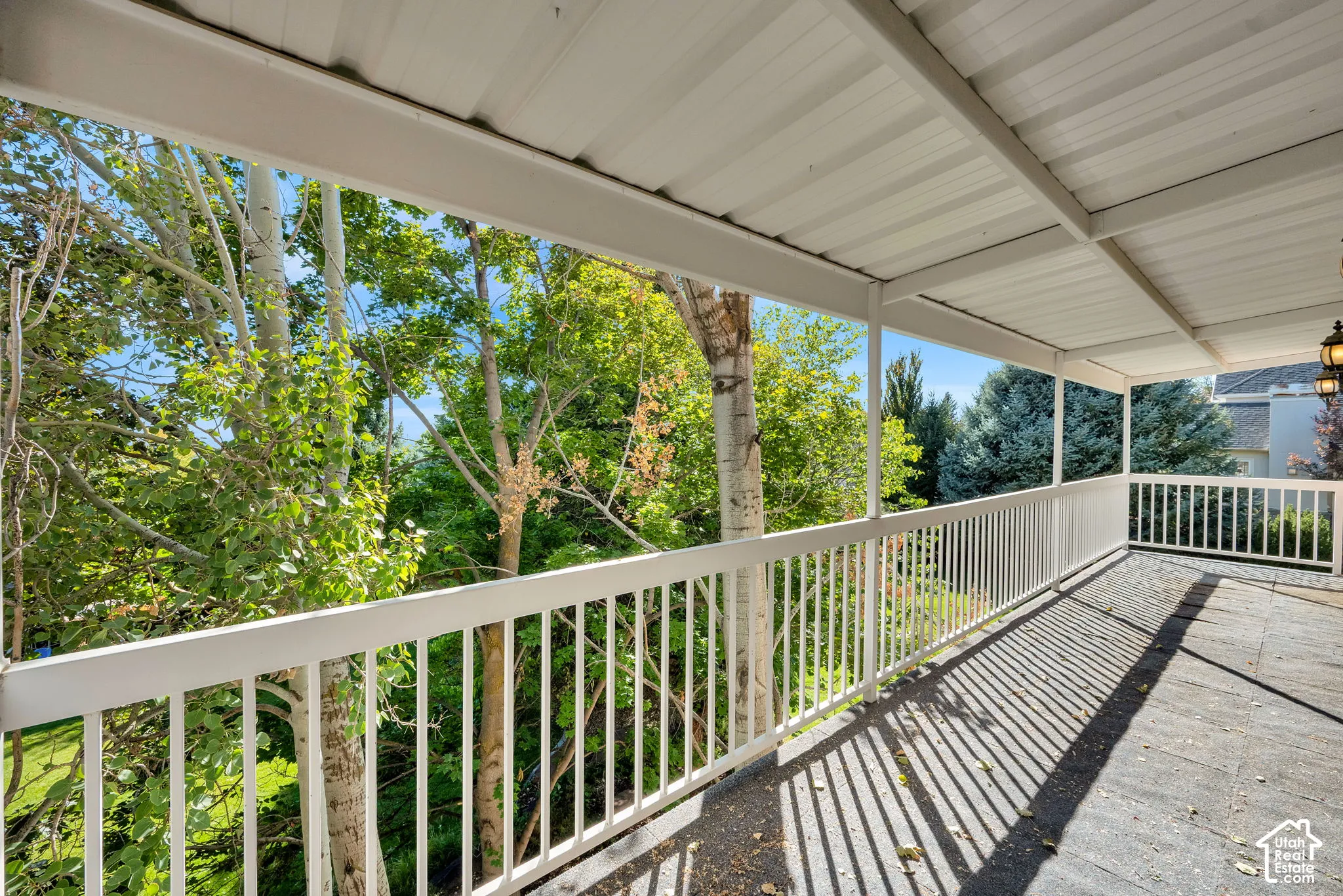 Covered outdoor patio with a white railing and overhead lighting