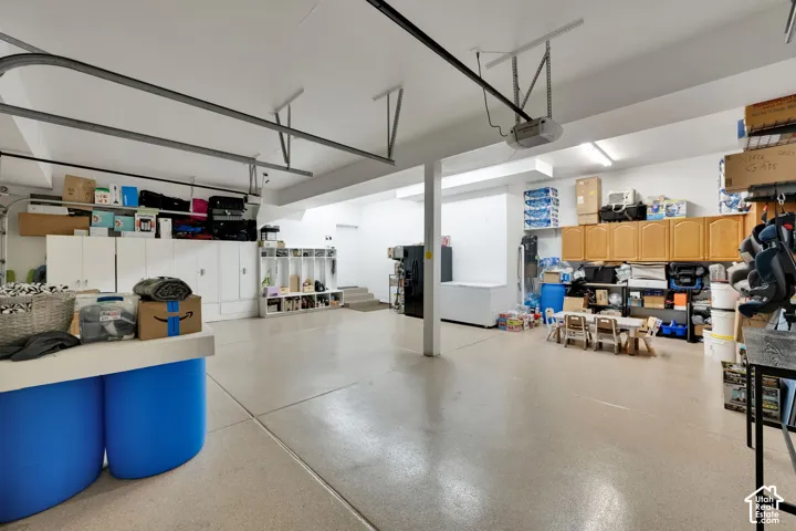 Spacious garage featuring a durable floor finish, extensive built-in cabinetry, and multiple overhead light fixtures