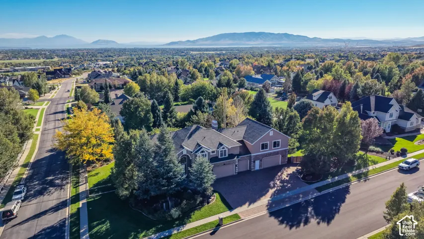 Residential property with a multi-car garage, mature landscaping, and a paved driveway