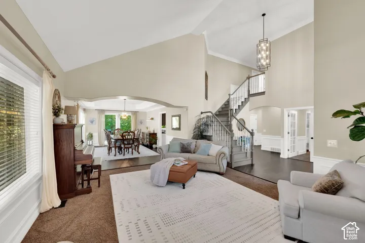 Vaulted ceilings, large windows, dark wood-finish flooring, staircase with white balusters, and an arched doorway