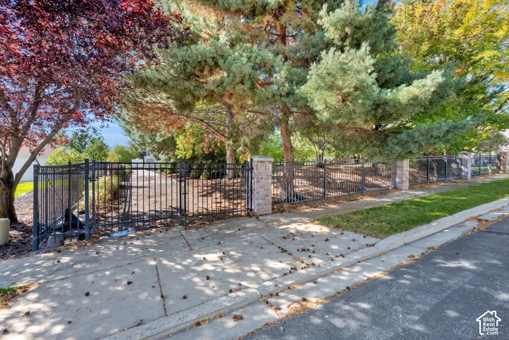Wrought iron fencing with brick columns, mature trees, and a concrete sidewalk