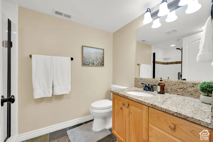 Vanity with granite countertop, integrated sink, and wood cabinetry