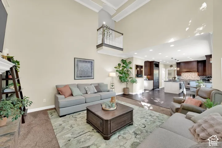 Soaring vaulted ceilings with architectural beams, open-concept design, kitchen with dark wood cabinetry and contrasting island, recessed lighting, and a stone-clad fireplace