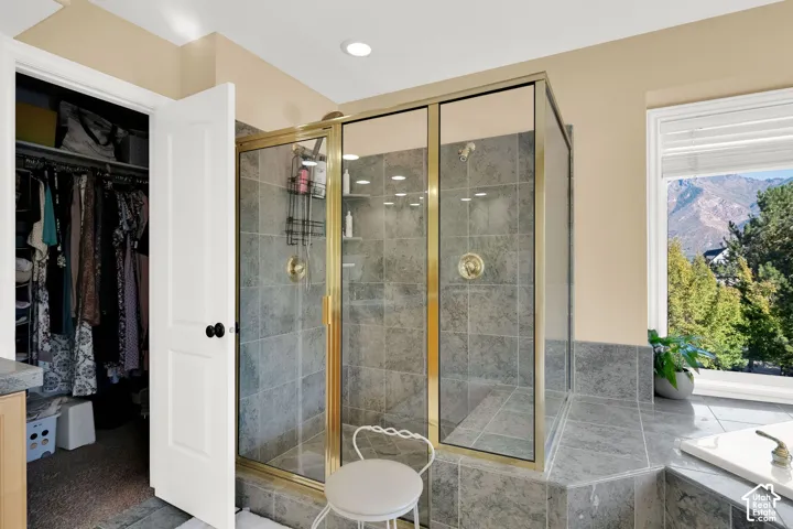 Glass-enclosed shower with gold-tone fixtures and tiled surround