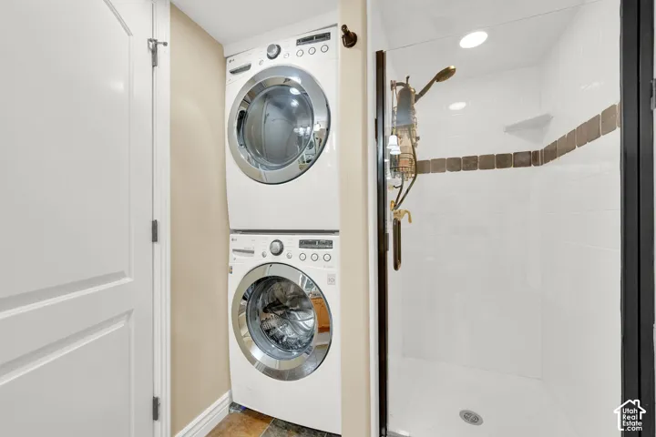Integrated stackable washer and dryer, tiled shower with accent band, glass shower enclosure, built-in shower shelf, and recessed lighting