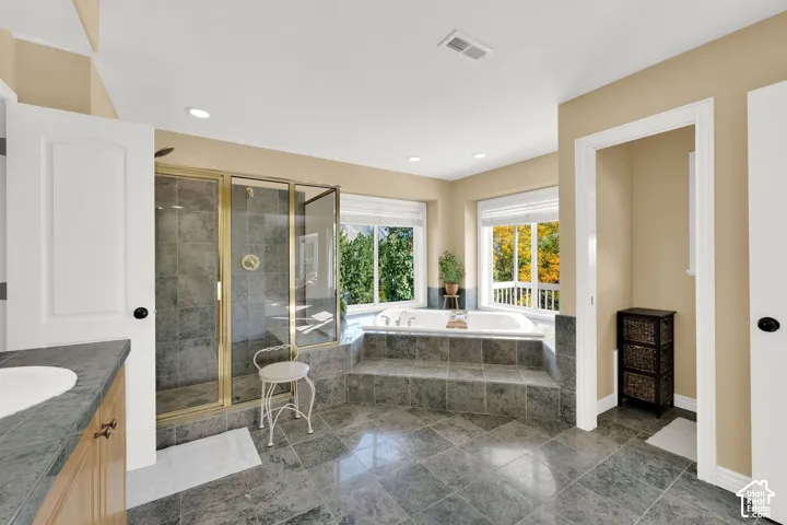 Recessed lighting, step-up bathtub platform, built-in soaking tub, glass-enclosed shower, and large windows