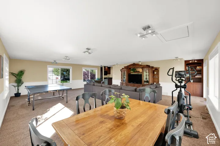 Spacious room with carpeted flooring, multiple windows, built-in shelving, and recessed lighting