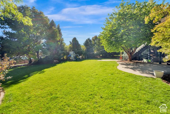 Expansive lawn bordered by mature trees and a concrete patio