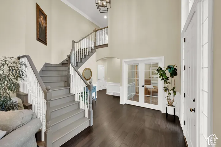 Two-story entryway featuring dark wood-finish flooring, a grand staircase with white balusters and gray handrails, and a modern chandelier
