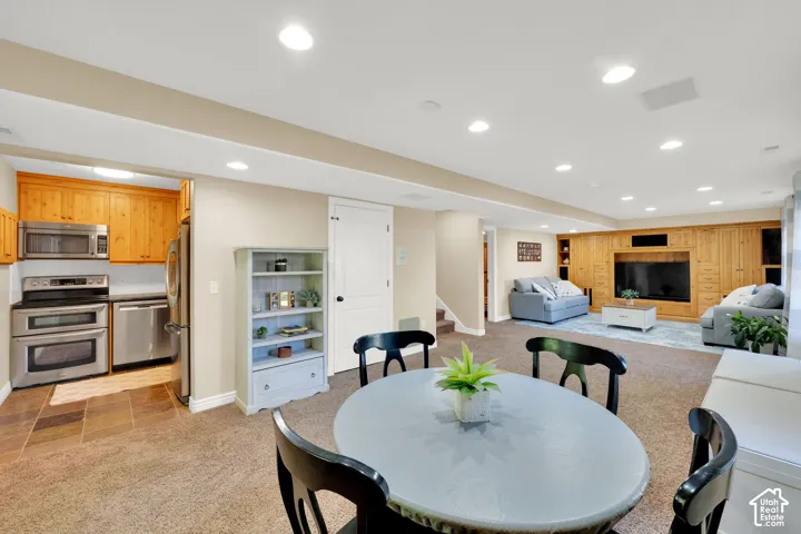 Open-concept living area with recessed lighting, integrated entertainment center, full kitchen with stainless steel appliances, and a built-in bookcase