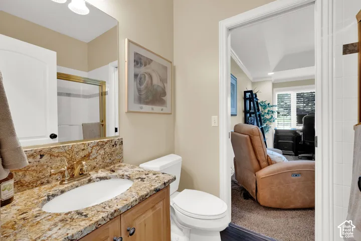 Vanity with a polished stone countertop and integrated sink, gold-tone faucet, and wood-finish cabinetry