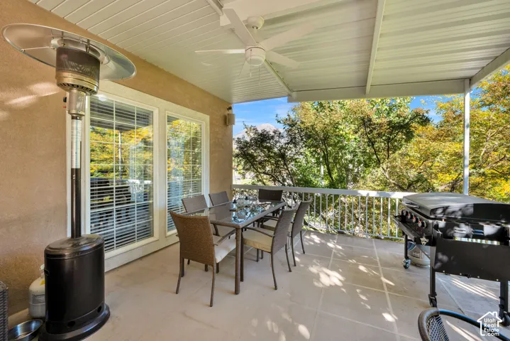 Covered patio with a ceiling fan, light-colored stucco exterior, and white railing