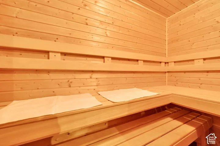 Interior sauna with light-toned wood paneling, multi-tiered wood bench seating, and wood slat flooring