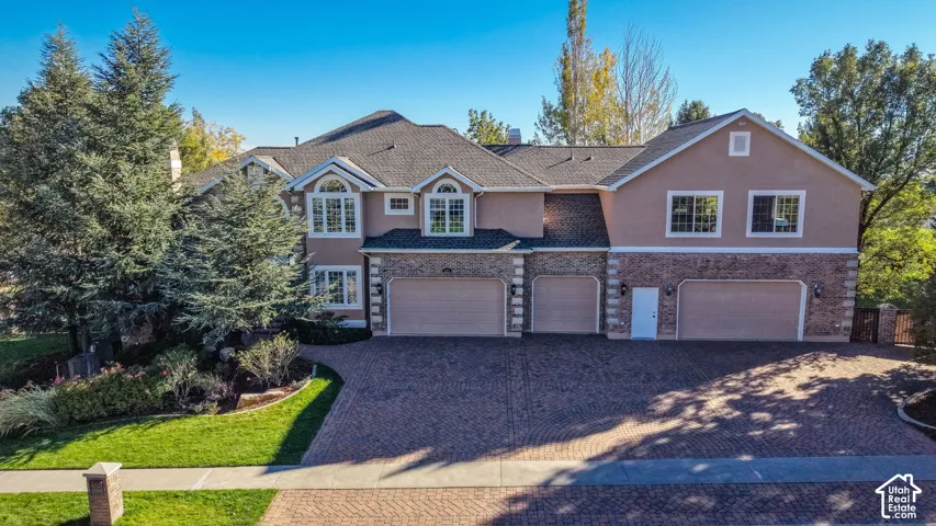 Multi-level residence featuring stucco and stone veneer, arched windows, and a multi-car garage