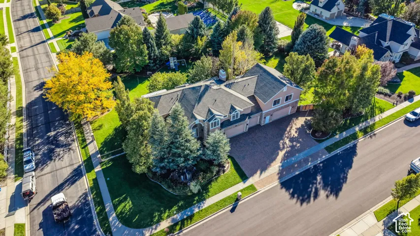 Siding exterior with brick driveway, attached garage, and mature landscaping