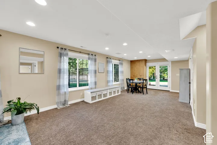 Recessed lighting throughout, two large windows, white trim, dual glass panel doors, and wood paneling detail
