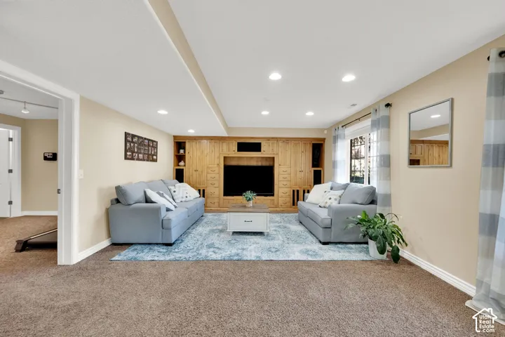 Recessed lighting, wood-finish built-in media center, neutral carpet, and light-toned walls