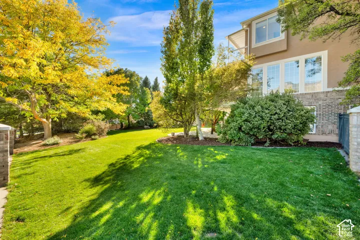 Expansive lawn area with mature trees, stone pillars, and manicured landscaping