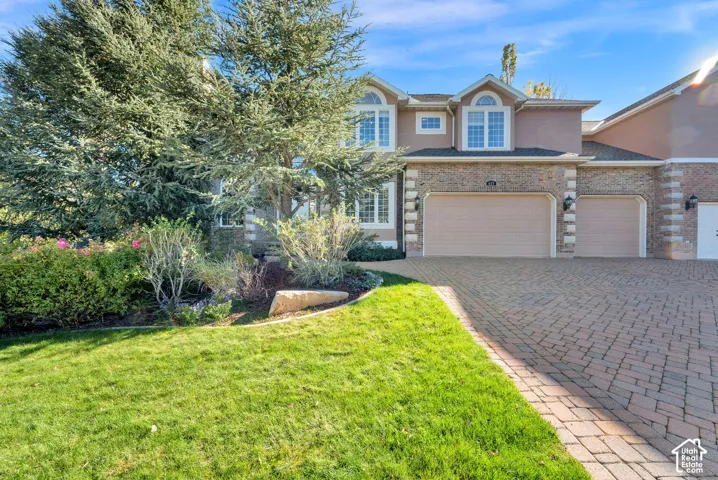 Stucco exterior with brick accents, arched windows, and a paved brick driveway