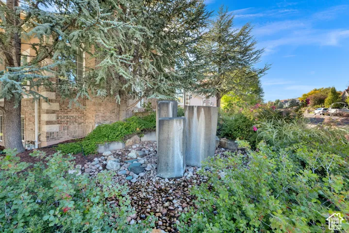 Brick exterior with stone accents, mature trees, and a decorative water feature with river rock