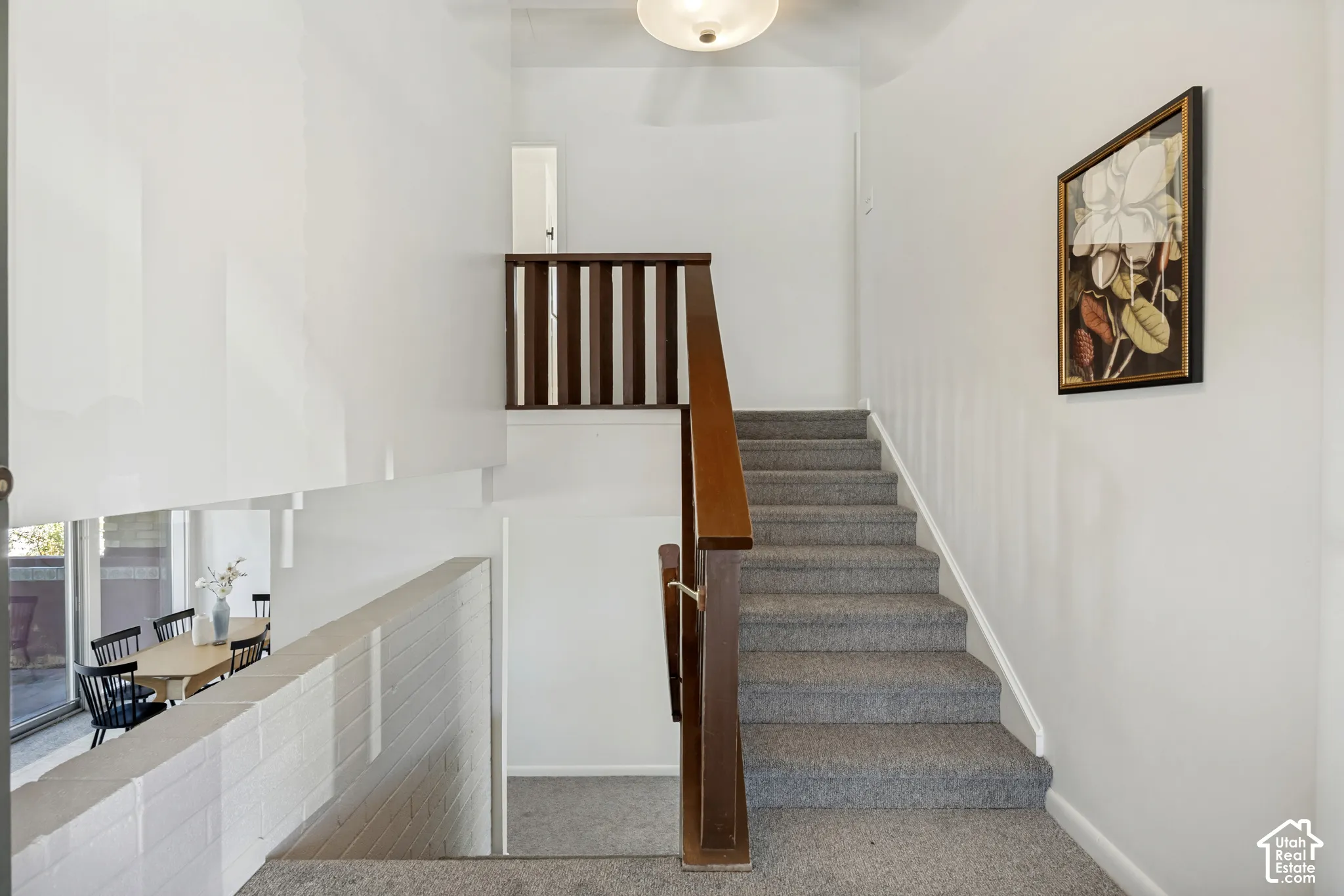 Split-level design featuring a carpeted staircase, wood banister, and a white brick half-wall