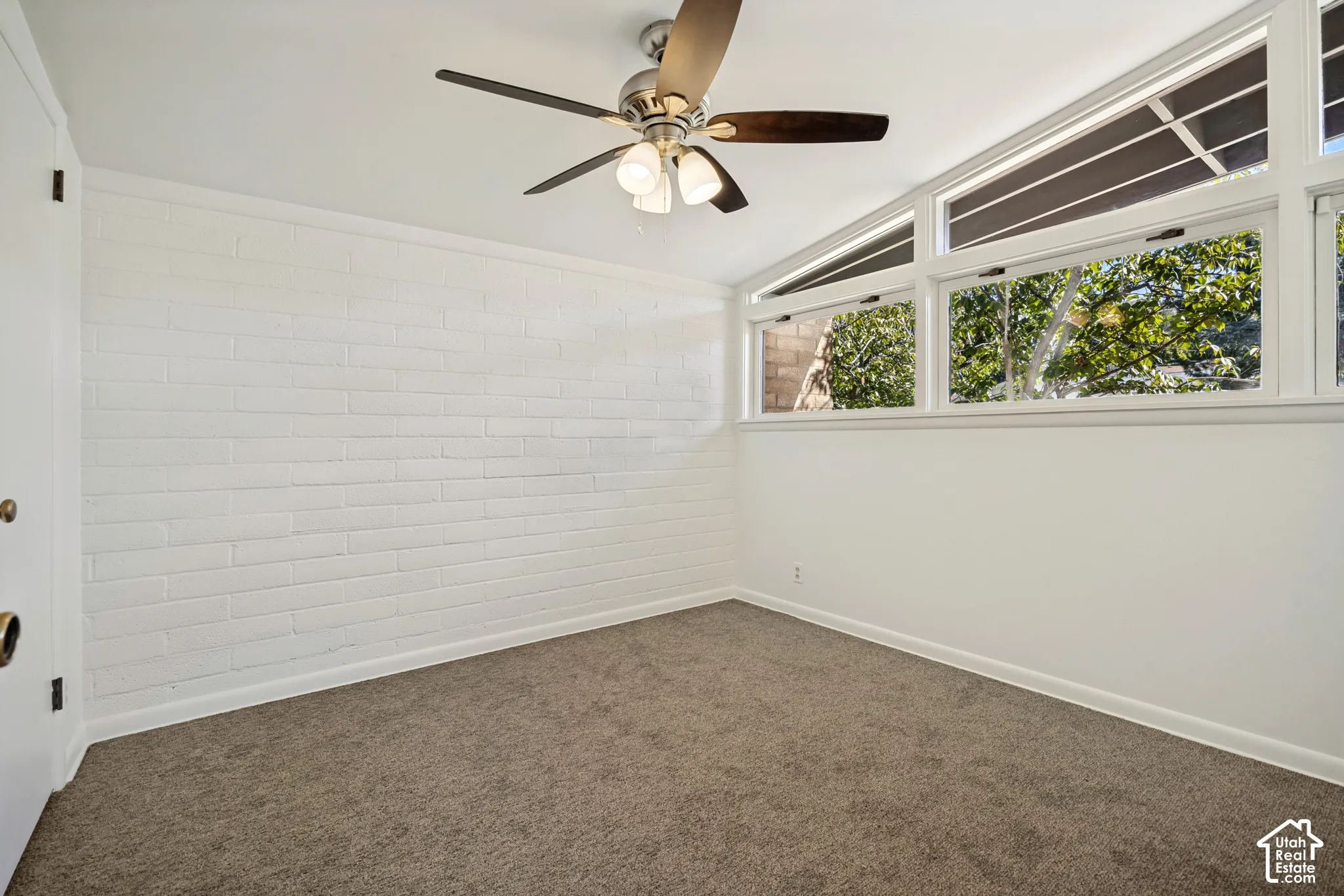 Recessed ceiling fan with integrated lighting, a full wall of white-painted brick, and multiple windows providing natural light