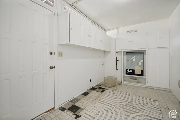 Wall-mounted white cabinetry providing storage, utility connections, and a paneled entry door
