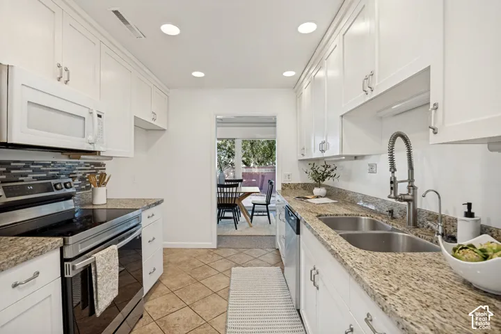 Kitchen featuring white cabinetry, granite countertops, tile flooring, stainless steel appliances, and recessed lighting