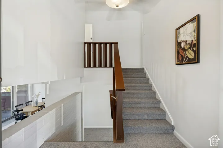 Split-level design featuring a carpeted staircase, wood banister, and a white brick half-wall