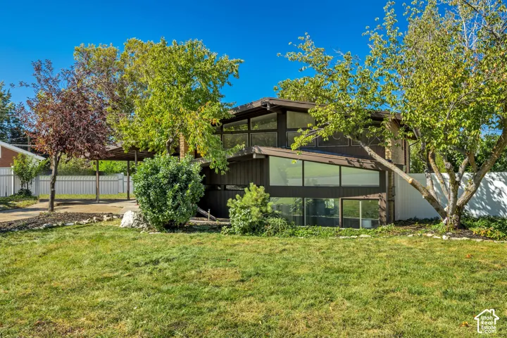 Multi-level exterior with extensive glazing, covered carport, and established landscaping