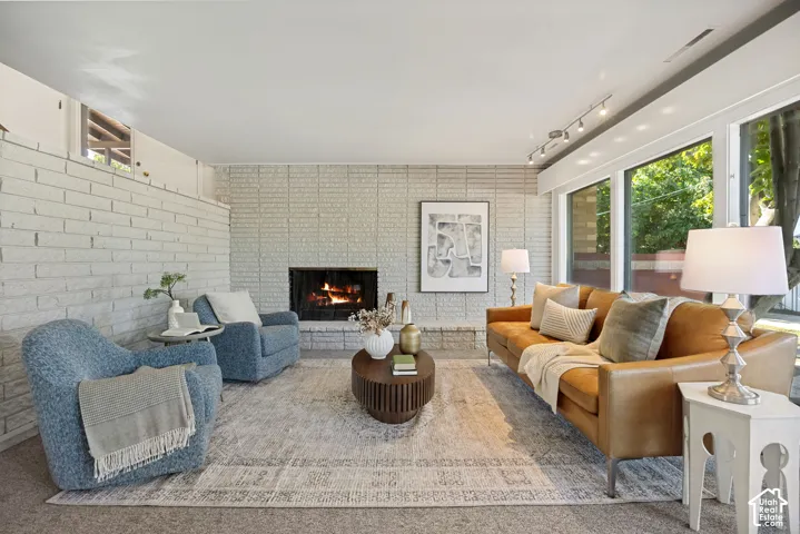 Painted brick accent walls, built-in fireplace, track lighting, and expansive windows