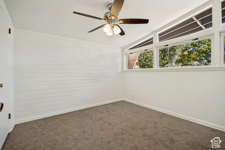 Recessed ceiling fan with integrated lighting, a full wall of white-painted brick, and multiple windows providing natural light