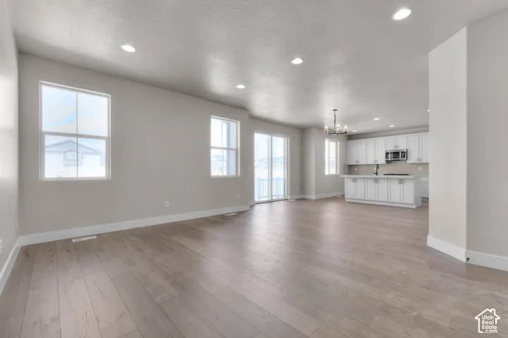 Spacious open-concept interior featuring light wood-finish flooring, recessed lighting, and large windows