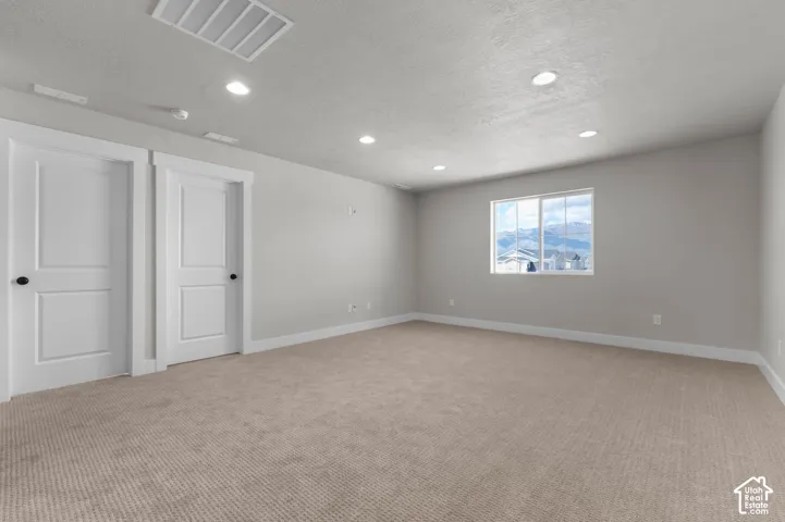 Recessed lighting, two paneled doors with dark hardware, a window with mountain scenery, and carpeted flooring