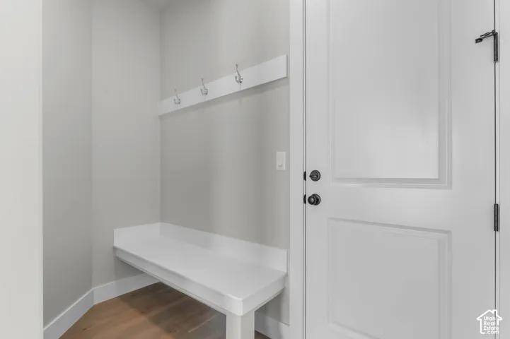 Built-in white bench seating with wall-mounted coat hooks and wood-finish flooring