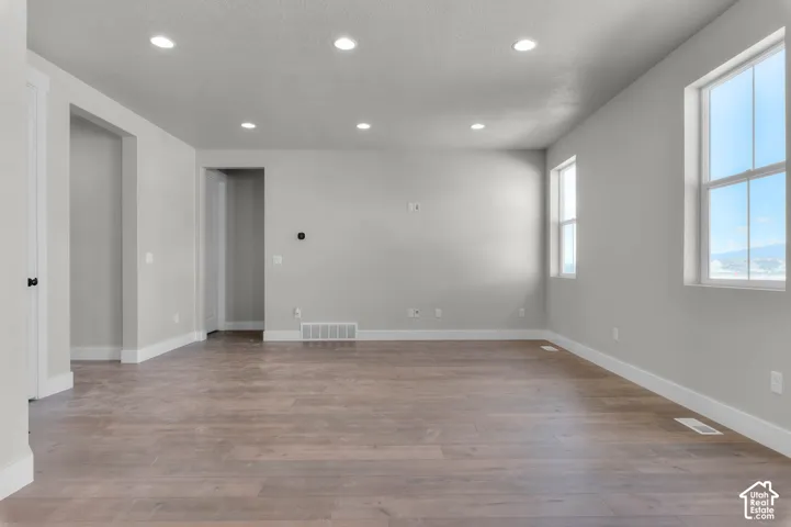 Recessed lighting, wood-finish flooring, light grey wall paint, and multiple windows