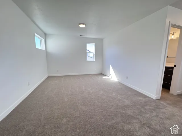 Spacious room with plush carpet, multiple windows, and recessed lighting