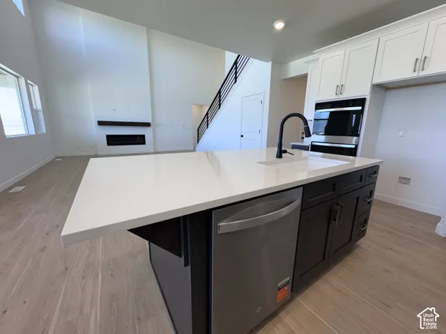 Kitchen island featuring a white countertop, built-in dishwasher, and matte black faucet
