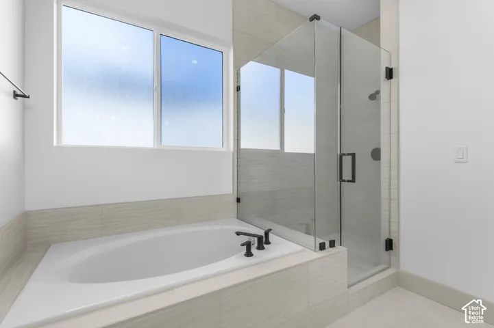 Built-in soaking tub with matte black fixtures, glass-enclosed shower, and tiled surround