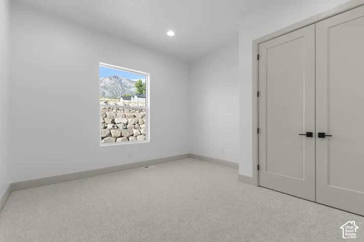 Recessed ceiling lighting, light gray wall-to-wall carpeting, white walls, and gray interior doors with matte black hardware