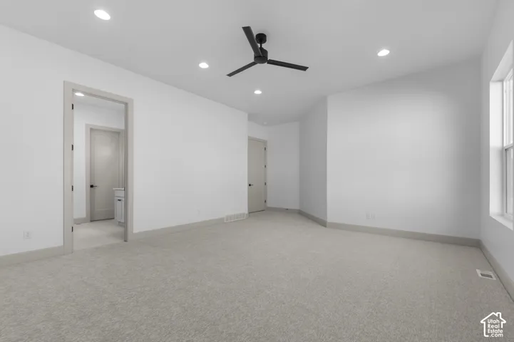Spacious room with light-toned carpeting, recessed ceiling lighting, a matte black ceiling fan, and painted trim