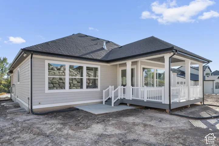 Covered patio with white railings, a concrete pad, and siding exterior