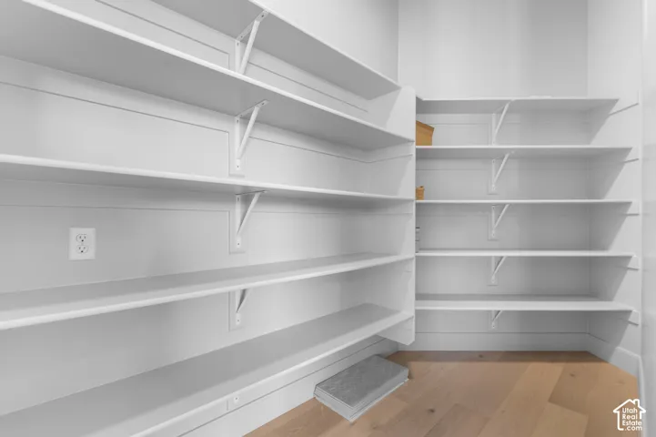White built-in shelving, light wood-finish flooring, and a wall outlet