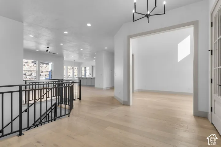 Open entry with light wood-finish flooring, recessed lighting, and a contemporary chandelier