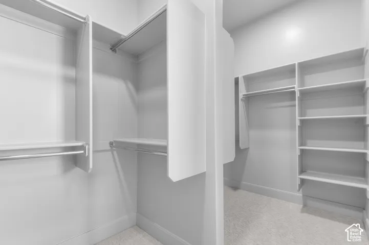 Walk-in closet featuring multiple hanging rods, built-in shelving, and carpeted flooring