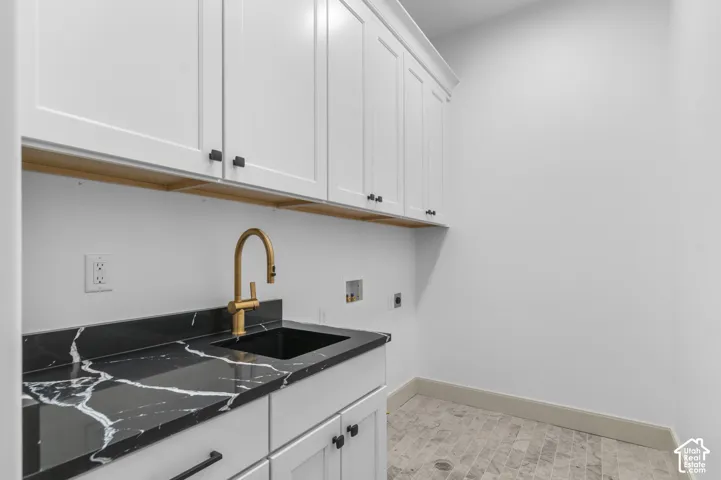 White shaker cabinetry, black countertop with white veining, gold-finish gooseneck faucet, integrated sink, and gray tiled flooring