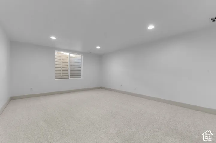 Recessed lighting illuminating the neutral wall-to-wall carpeting and white walls
