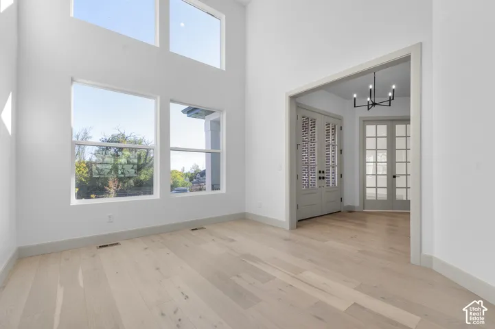 High ceilings, abundant natural light, wood-finish flooring, French doors, and a modern chandelier