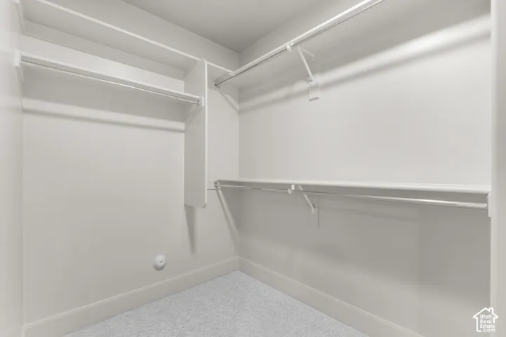 Built-in shelving and hanging rods, white walls, and light-colored carpeting