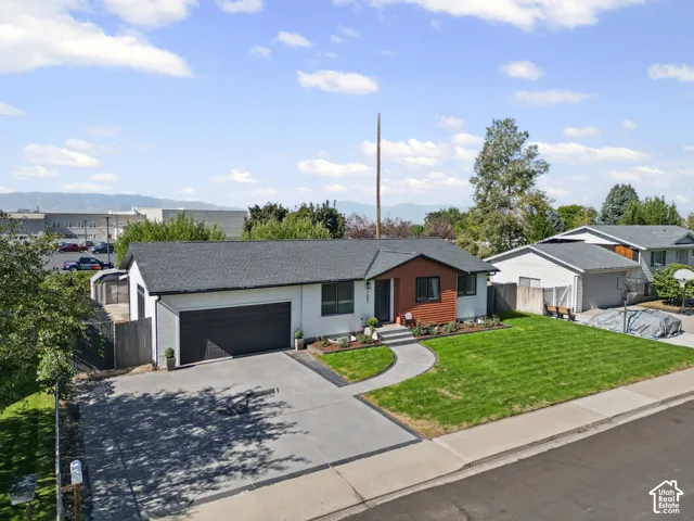 Contemporary exterior with contrasting siding, dark shingle roof, integrated garage, concrete driveway, and a manicured lawn